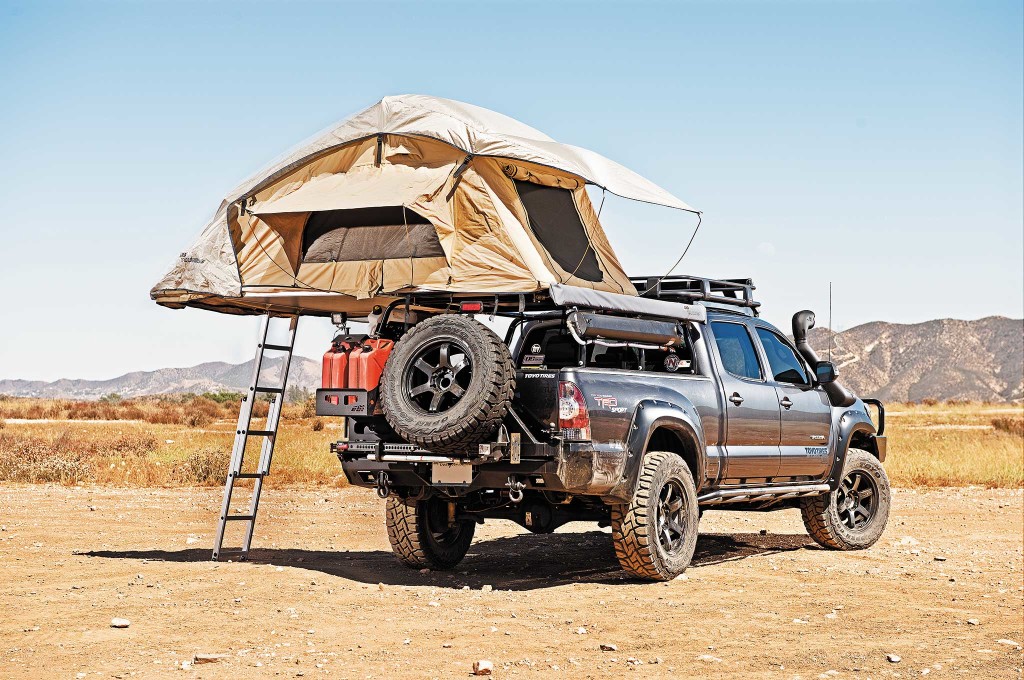 The All Pro-Off Road Expedition Series Pack Rack bed rack helps create organized storage space over the truck bed without compromising hauling capacity. A bevy of gear is attached to it, including an ARB Series III Simpson Roof Top Tent, ARB Awning 2000, and a Road Shower.
