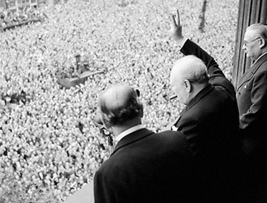 Sir Winston Churchill waving to the crowds, seen with his signature cigar.