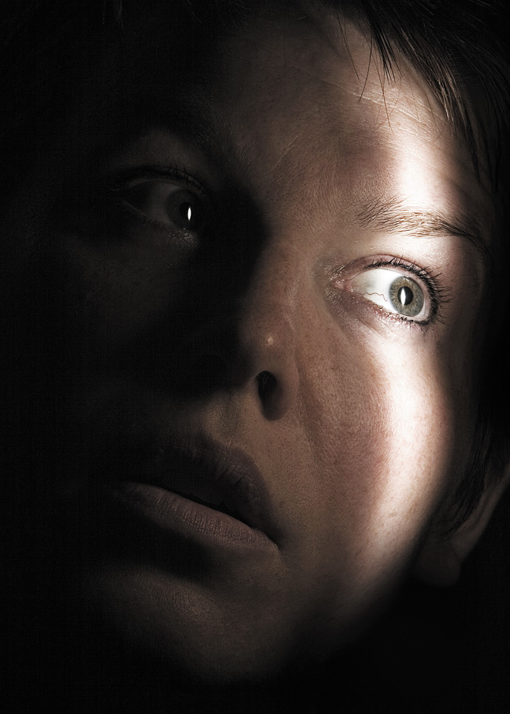 woman-scared-hiding-with-beam-of-light-on-her-face